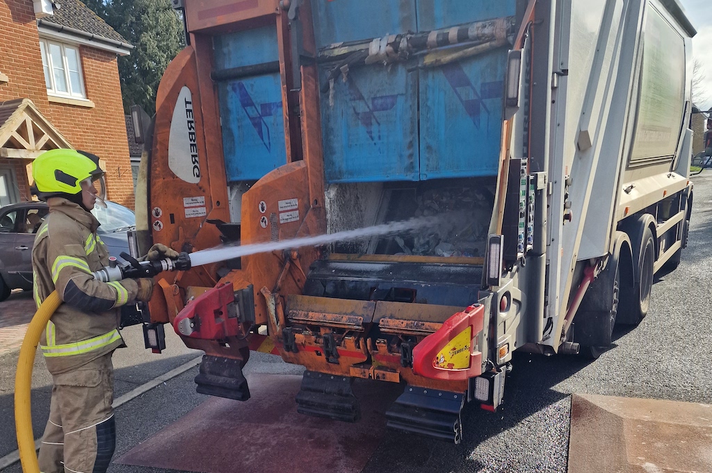 Firefighter putting out flames in the back of a Canenco refuse lorry