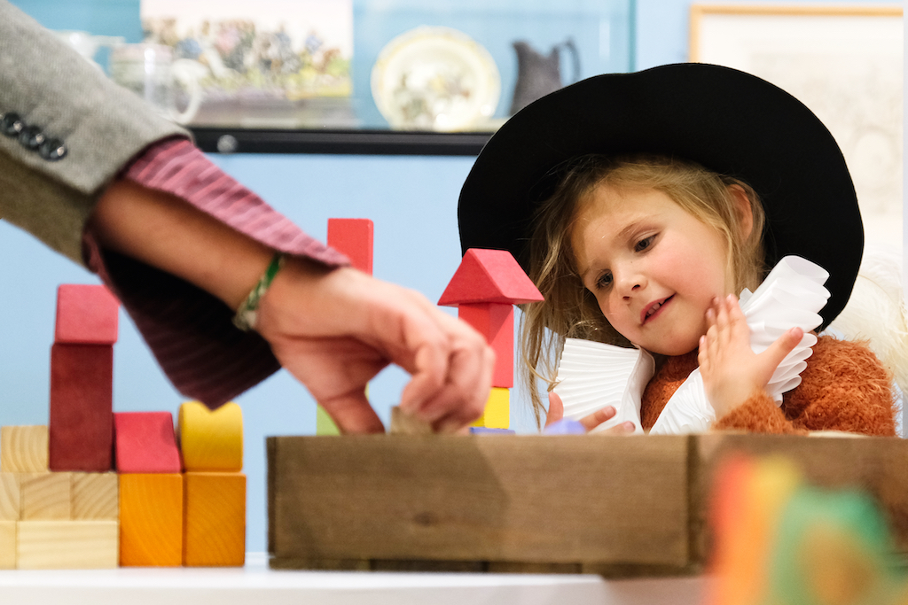 Child is dressing up clothes playing with building blocks at The Beaney museum