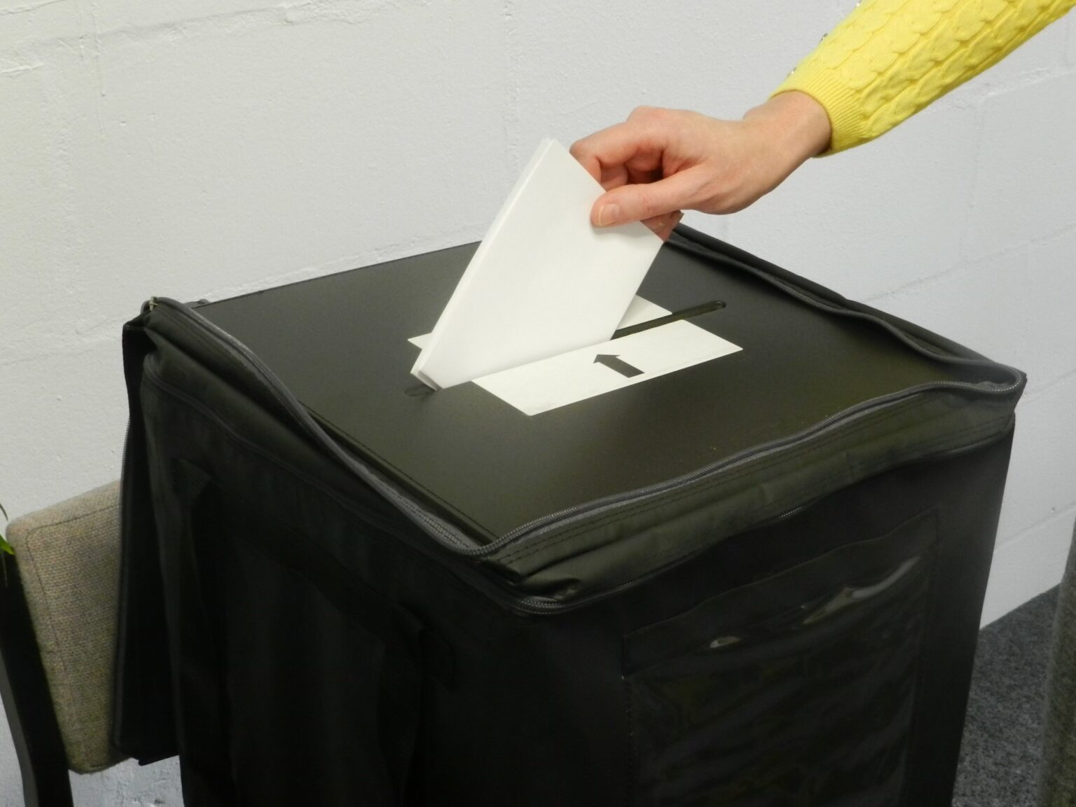 A hand putting a polling card in a ballot box