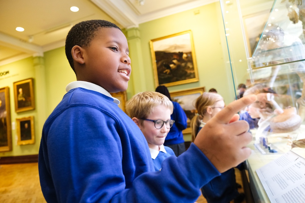 School children looking at display cabinets at The Beaney