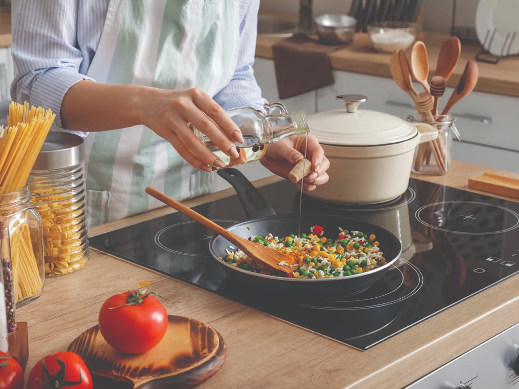 Person adding cooking oil to food in a frying pan