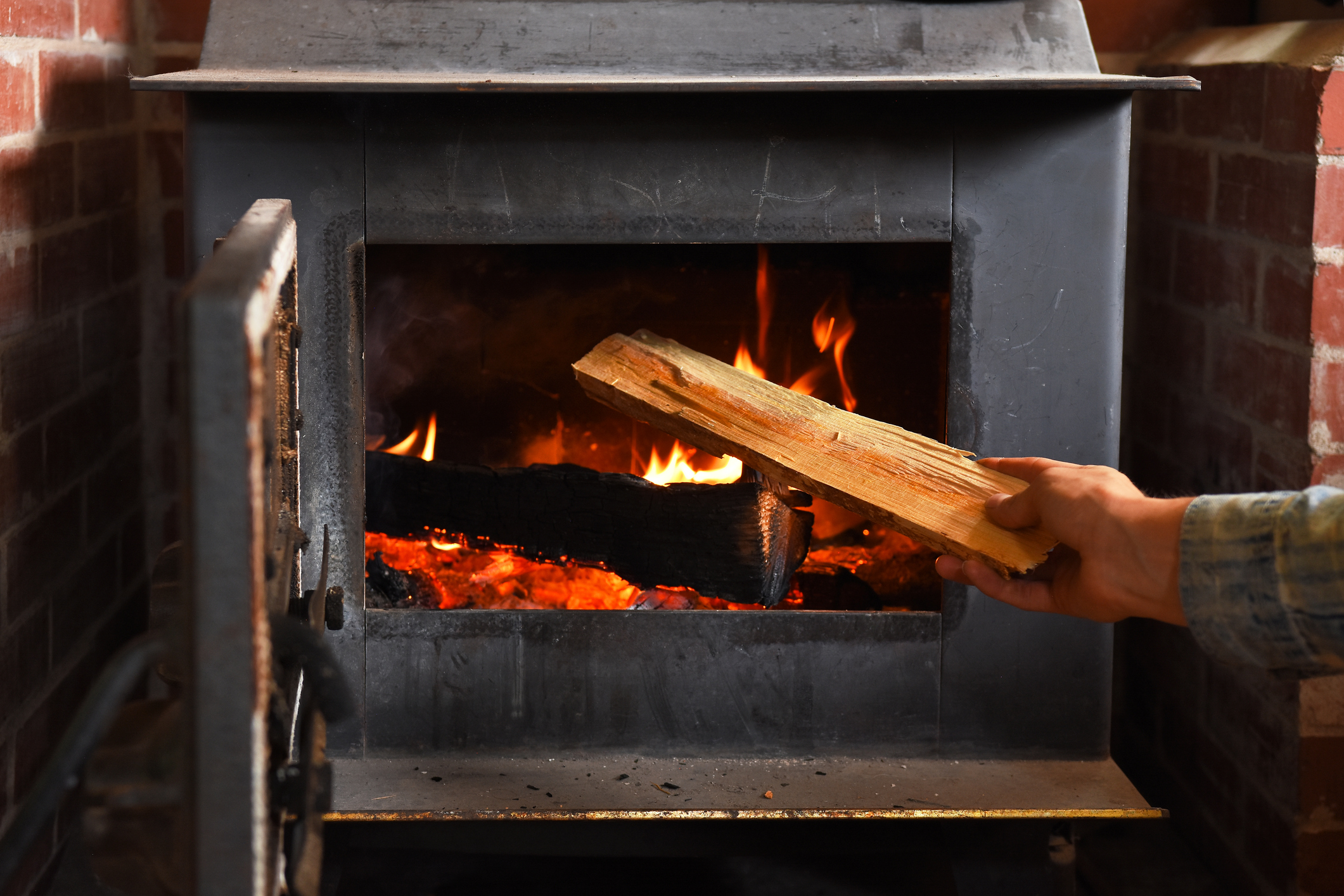 Person putting wood in a wood burning stove