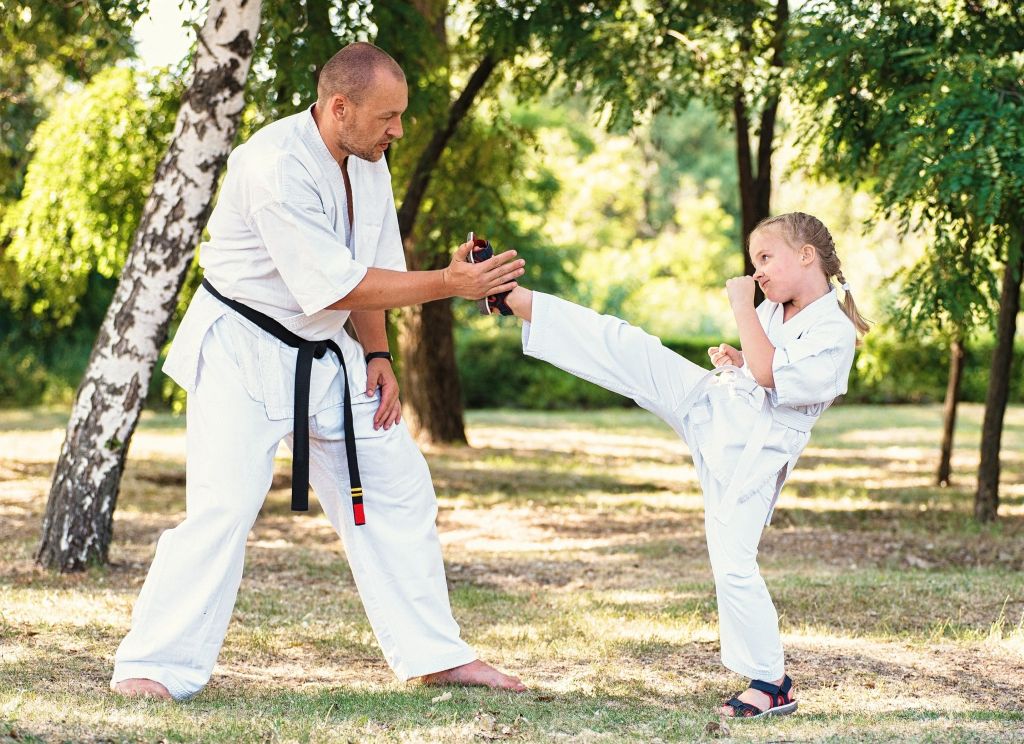 Adult taekwondo teacher teaching a child how to kick
