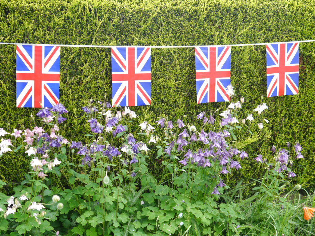 Union Jack flag bunting hanging against a hedge