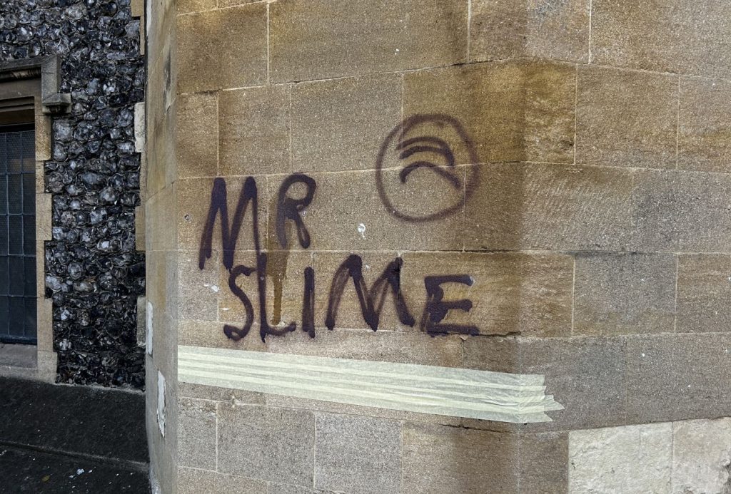 Graffiti tag on a wall saying 'Mr Slime' 