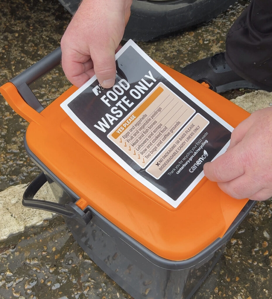 Canenco staff putting a sticker onto a food waste bin