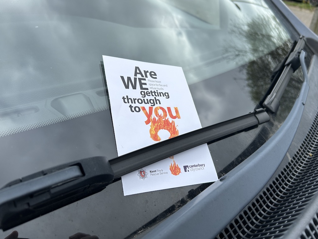 Flyer that says 'Are we getting through to you?' left on a car that is blocking road access