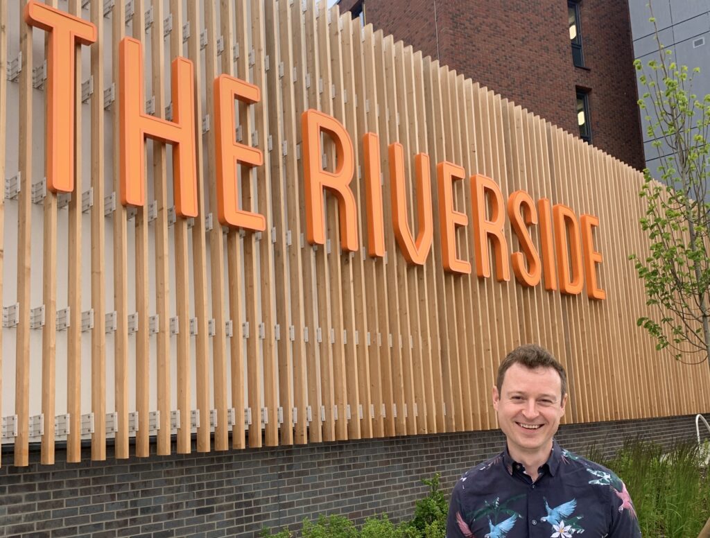 Cllr Ben Fitter-Harding in front of The Riverside sign