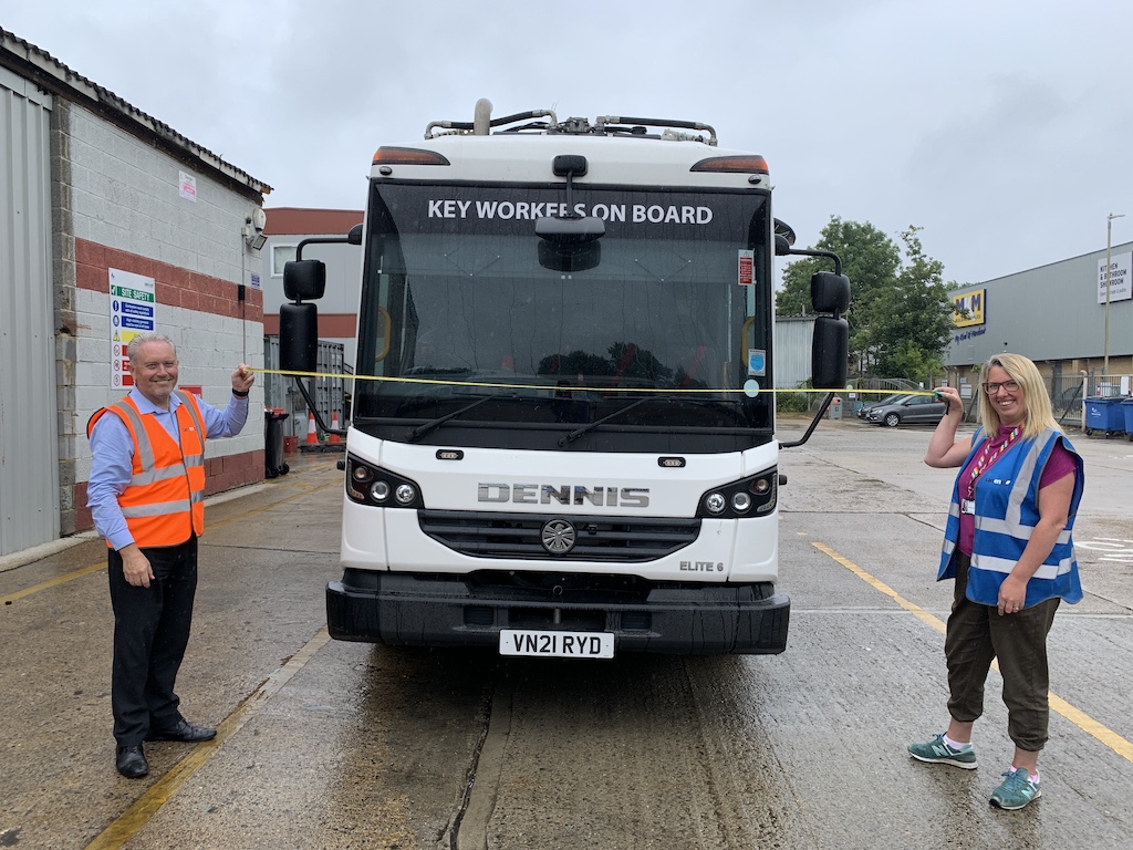 Cllr Charlotte Cornell and Canenco staff member holding a tape measure across the front of a recycling lorry to show the 4-metre gap needed for a fire engine to operate at an incident