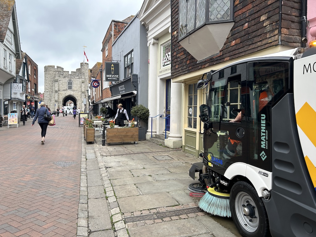 Bin man operating a street sweeper with the Westgate Towers in the background