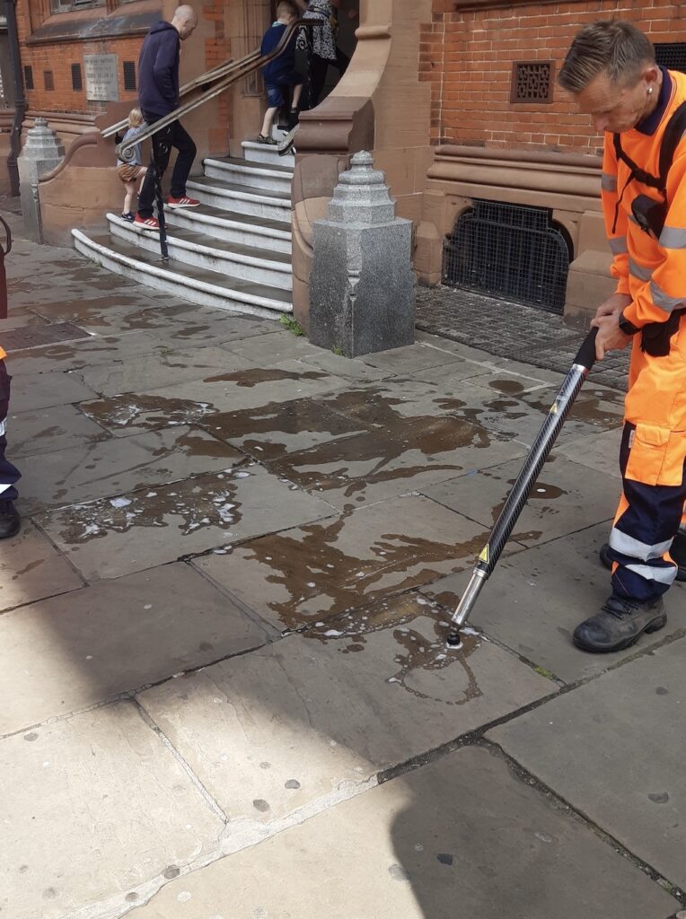 Street cleaner removing chewing gum stains with special equipment