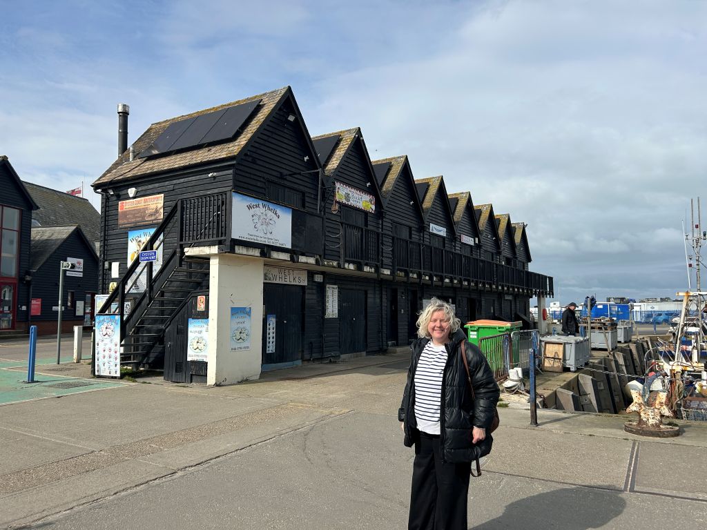 Cllr Mel Dawkins standing in front of the fisherman's huts with the new solar panels installed