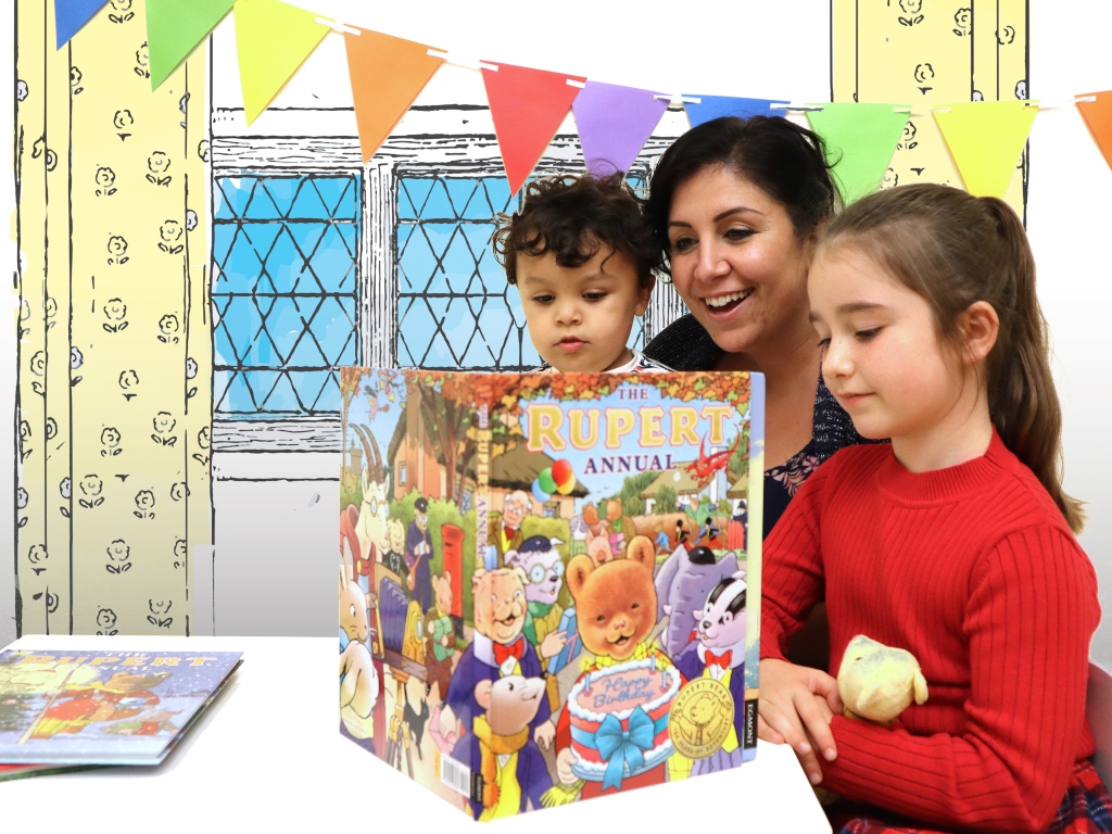 Mother and two children reading a Rupert Bear annual