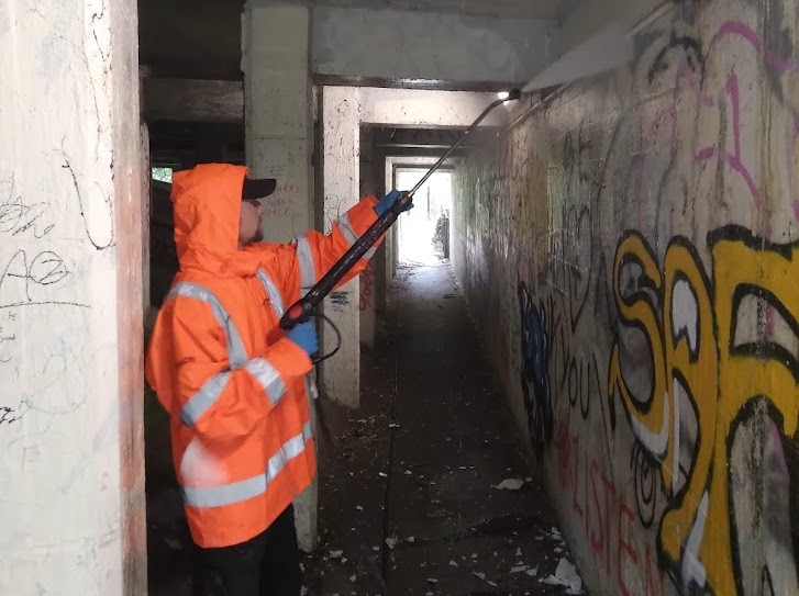 Council worker cleaning graffiti off the bridge with spray equipment