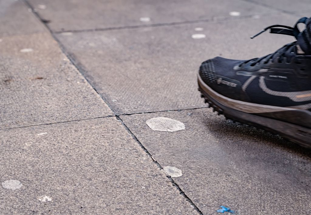 Gum stains on a floor with a trainer that is about to step on a stain