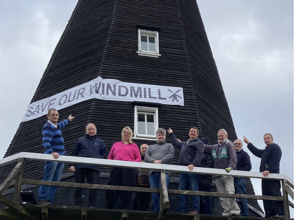 Canterbury City Councillors and Friends of Herne Mill group members standing in front of Herne Mill with a banner that says 'Save our Windmill'