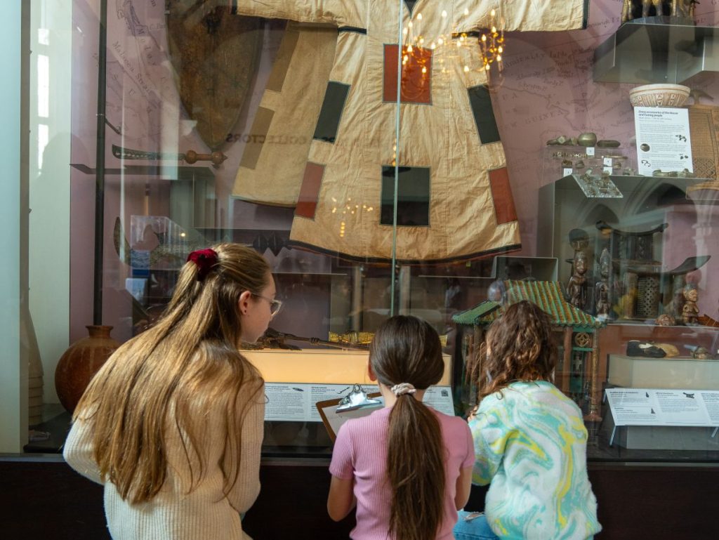Three children looking at a museum cabinet at The Beaney